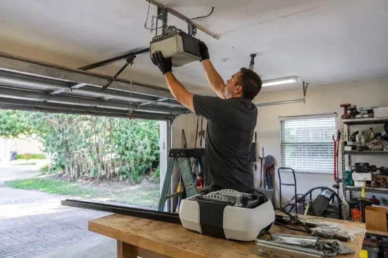 Person holding an overhead garage-door opener beside another opener and hardware on a workbench — Garage Door Opener Replacement, Markham
